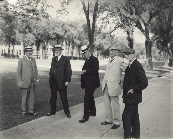 A group of men poses on Bascom Hill on the University of Wisconsin-Madison campus. Left to right: UW President Charles R. Van Hise, UW President Thomas Chrowder Chamberlin, Dean H.L. Russell, Dean William A. Henry and Stephen Moulton Babcock. They are all wearing suits and hats.