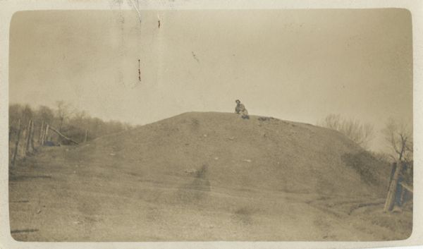 A man sits on top of a mound near Trade Lake.