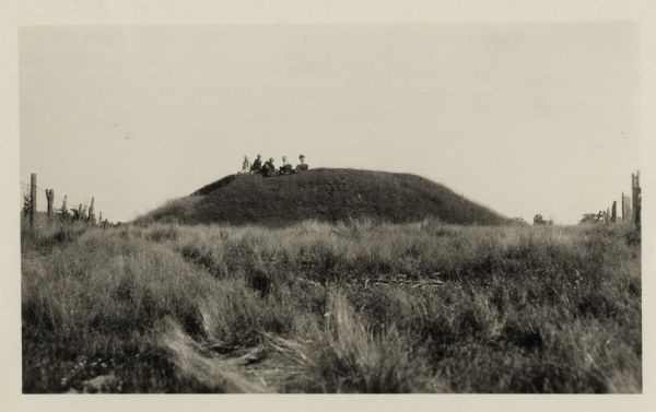 Three men and two women sit on top of a mound near Trade Lake.