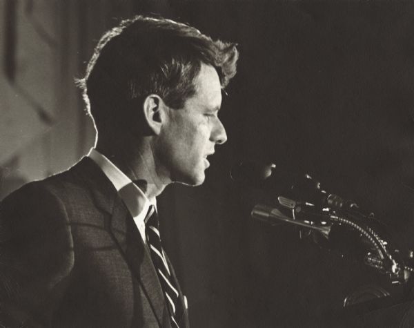 Side view of Robert F. Kennedy speaking at a podium.