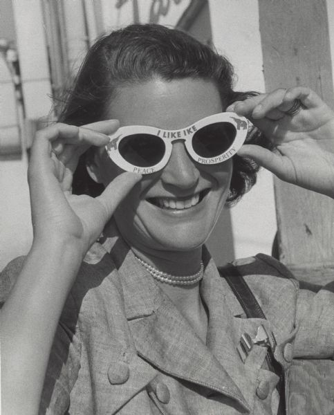 Mrs. Philip G. Kuehn, Whitefish Bay, wife of the state Republican party chairman, wore "I Like Ike" sunglasses while sightseeing. The glasses have elephants in the corners and the words "I Like Ike, Peace and Prosperity" on the front.