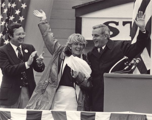 A brief shower failed to dampen the enthusiasm of Democratic Presidential candidate Walter Mondale and Vice-presidential candidate Geraldine Ferraro during a campaign visit. Applauding them is Congressman David R. Obey who represented that area in Congress.