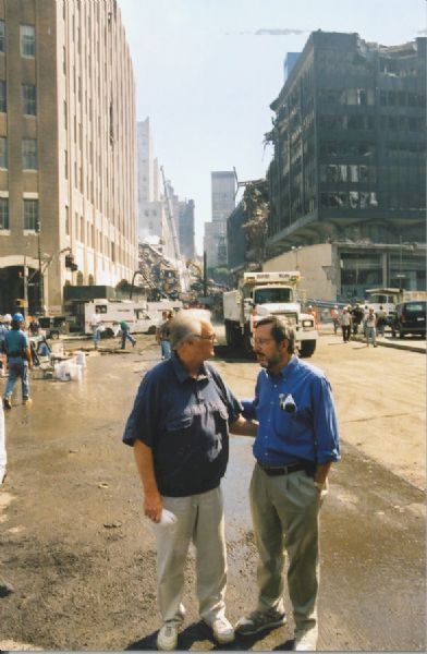 Florida Congressman Bill Young (left) and Wisconsin Congressman David R. Obey, respectively the Republican chair and the ranking Democrat of the House Appropriations Committee, at 9/11 Ground Zero only a few days after the attack. Obey and Young were present in conjunction with their role in authorizing emergency federal funds. Behind Obey is the World Trade Center 6 building (6 WTC) and on the left is the Verizon Building. Both were heavily damaged by the collapse of the twin towers. 6 WTC was razed; the Verizon Building, an architectural landmark, was restored. Behind the Verizon Building is the debris pile of the World Trade Center Building 7 (7 WTC) which collapsed during the afternoon of September 11 because of fire. The view here is looking east on Vesey Street.
