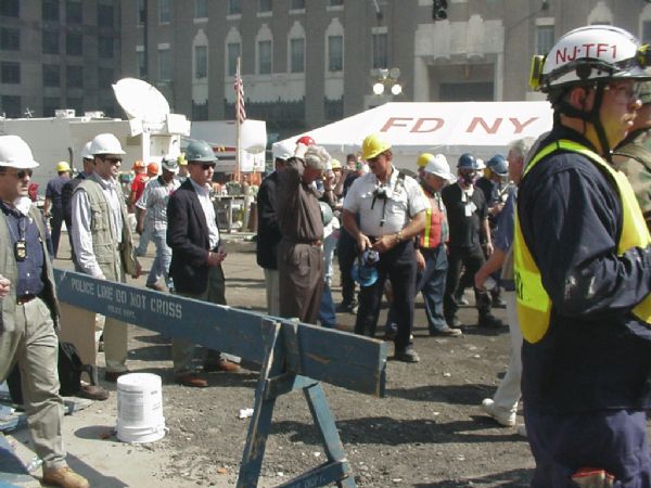 Former President Bill Clinton, in the center without a hardhat, touring conditions at Ground Zero a few days after 9/11. In the background is the Verizon building which was damaged by the collapse of the 7 WTC building.