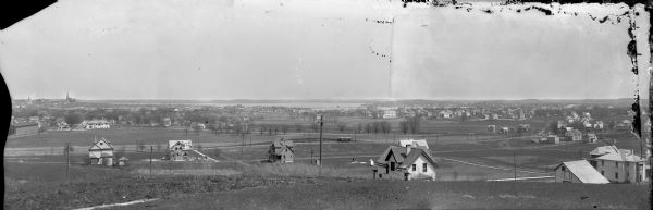Panoramic view of Madison taken from Summit Avenue looking East South East toward Lake Monona. Included in the view are the Camp Randall bleachers, St. Raphael Cathedral, the Dane County Courthouse, Fire Station #4, Madison General Hospital, St. James Church, Longfellow School, and many private residences. Parallel to the frame is Breese Terrace and Randall Streets. There is an electric street car on the track heading Southwest.