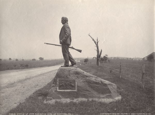 Statue of John L. Burns, the elderly citizen-hero of the Battle of Gettysburg, who fought with the 7th Wisconsin on July 1, 1863 and was wounded. A veteran of the War of 1812, Burns survived his Civil War combat to become a national hero and his carte-de-visite was highly prized. In 1903 the state of Pennsylvania honored Burns with this statue. The photograph, which looks north toward the equestrian statue of General Reynolds, also shows the appearance of the battlefield at the turn of the century.