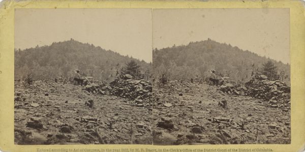 Stereograph of Round Top Mountain, near the site of the Gettysburg battlefield. A man sits on a stump, shading his eyes with his hand, gazing at the mountain. Handwritten on the reverse is "Round Top Mountain, (left of our line)."