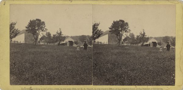 Stereograph of the McPherson farm buildings near the site of the Gettysburg battlefield. Two figures appear on the right side: Mathew Brady standing and his assistant sitting. Seated in front of the wagon shed are two figures, these may be John and Eliza Slentz. Handwritten on the reverse, "Where Gen. Reynolds died."