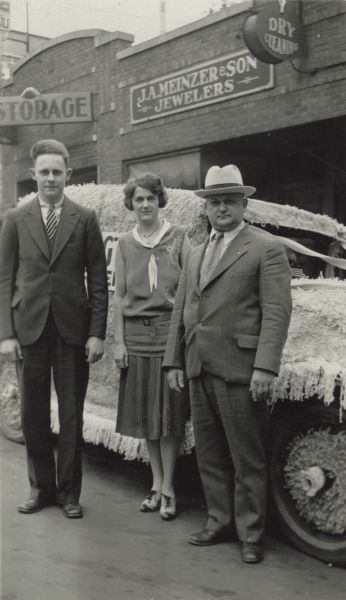 Stanley Stemp (right) and two employees stand in front of a truck that was decorated for a parade put on by Madison businesses. They are parked in front of 3F Dry Cleaners, J.A. Meinzer & Son Jewelers and a Storage Company.