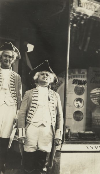 Stanley P. Stemp (right) and an employee dressed as patriots for a Washington's birthday sale parade. They are posed next to the Stemp Typewriter Company window.