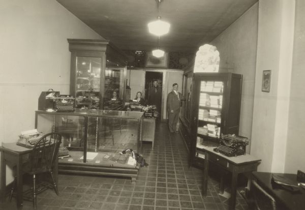 Stanley P. Stemp (owner), standing on the right, and two employees in the Stemp Typewriter Company located at 533 State Street. This store was the first and was referred to as the "Little Store" by the owner and staff.