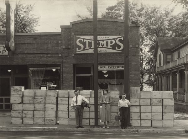 Stanley P. Stemp (owner), on the left, and two employees stand on the sidewalk in front of the Stemp Typewriter Company located at 533 State Street. They had just received a large delivery of office machines.