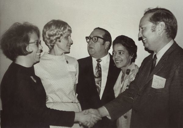 Vel Phillips in a group. The man and woman in the foreground are shaking hands. The men are wearing suits and the women are wearing dresses. Several have name tags.