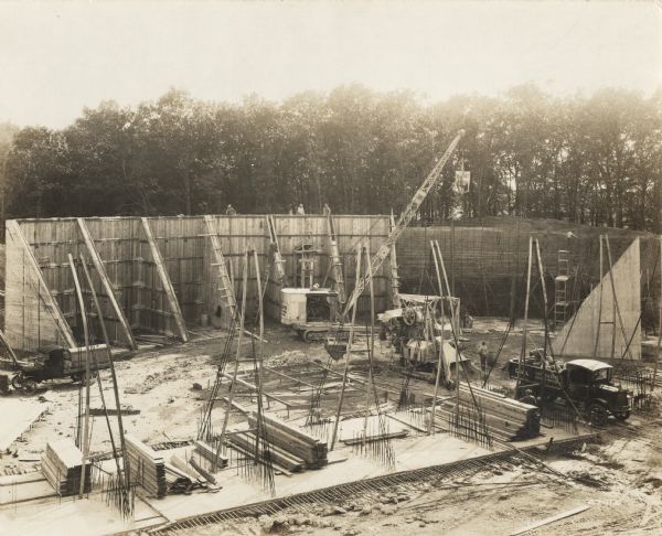Elevated view of a building site with "O'Dea and Shafer, Engineers and Contractors" construction crew, crane and other equipment. On the photograph album binding on the left side of the photograph is written "Reservoir at Madison."