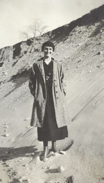 A woman, Grace, smiles as she poses while standing in a sand pit near the intersection of Fish Hatchery Road and Park Street. A note on the back of the photograph reads, "Dividing Ridge, Sand Pit, Pieh's Hill/Keyes Hill."  John Pieh and the Keyes Brothers were in the sand and gravel business.