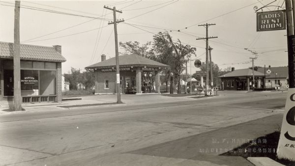 Businesses located near the intersection of Park and Lakeside Streets, before Park Street was widened. Identified from left, Madison Do-Nut Kitchen, Valvoline Filling Station and (probably) Standard Oil Filling Station. The photo was taken from the opposite side of Park Street, (probably) Hellickson's Gas Station. Note the street car tracks and wires curving onto Lakeside Street, between the two filling stations, from Park Street. A sign for a Ladies Rest Room appears in the upper right corner.