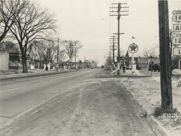 South Park Street (Hwy 12 & 14 & 18) looking south from the intersection at Midland Street. On the left across the street is Southside Pharmacy at 1123 South Park Street, and further down the street is Moore's Wadham's Mobilgas Service Station at 1129 South Park Street. On the right is Bartsch's Texaco Station at 1118 South Park Street, and next door is Walter Plaenert's Grocery at 1128 South Park Street.