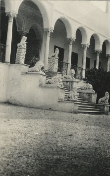 The ornate entrance to the building where the bey (chieftain) holds court in Bardo, Tunis. Carved stone lions are perched on both side of the staircase. Columns and arches line the front edge of the porch. More arches appear within the entrance.