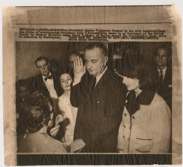 Original UPI Wirephoto transmission. Caption reads: "Vice President Lyndon B. Johnson flanked by his wife Ladybird (L) and the widow of assassinated President John F. Kennedy (R) is sworn in as President of the United States by Federal District Judge Sarah T. Hughes of Dallas aboard the Presidential plane prior to returning to Washington."