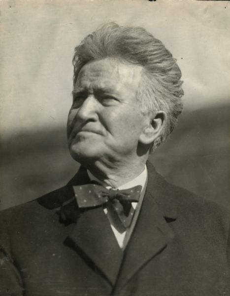 Quarter-length portrait of Robert M. La Follette, Sr. He is wearing a suit coat and bow tie. To the left of the photograph in the scrapbook is written, "For There is a Man Whose Labor is in Wisdom, and in Knowledge, and in Equity. Ecc. 2-21."