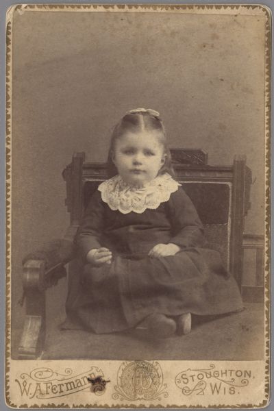 Cabinet card with full-length formal studio portrait of young Beulah Irene Miller (1888-1858). She is sitting in a chair with her hands in her lap. Her dress has a lace collar and she wears a bow in her hair.

Beulah was born January 18, 1888 in Evansville, Wisconsin, the daughter of Willis Exteen Miller (1859-1932), a farmer, and Sarah Maria Altemus (1857-1933).  On February 21, 1912 Beulah married Charles Guy Thomas (1879-1925), a dairy farmer.