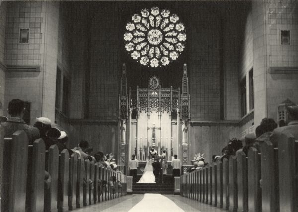 An interior image of St. Catherine Catholic Church during the marriage ceremony of Mary (Kustermann) Esser (b. 1934) and J. Thomas Esser (b. 1934).