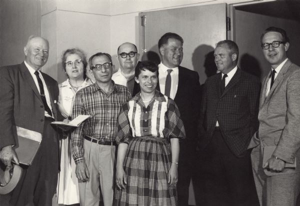 Group portrait of men and woman at a Wisconsin Fellowship of Poets convention. Names, (l to r): Marvin Davis Winsett, Poet Laureate of Texas; Edna Kristin Meudt, Wisconsin, President of the National Federation of State Poetry Societies (NFSPS); Edward Uhlan, Exposition Press; Dr. John Grinde, Convention Chairman; Jo Bartels Alderson, President, Wisconsin Fellowship of Poets; August Derleth, Wisconsin writer and convention speaker; Dr. Purcell, holder of Chester Nimitz Chair at Naval War College; and Dr. Max Golightly, Vice Chancellor of the NFSPS.