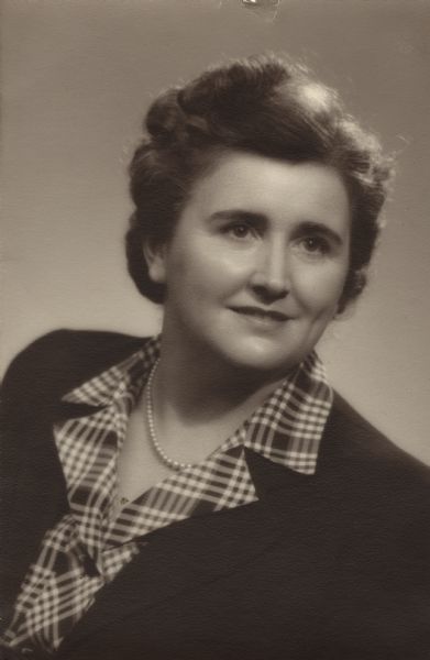 Quarter-length studio portrait of Edna Kristin (Kritz) Meudt. She was the President of the National Federation of State Poetry Societies (NFSPS). She is wearing a dark jacket, plaid shirt and pearls.