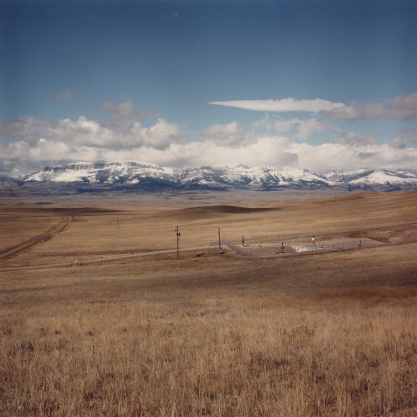 View across valley towards missile silo, Minuteman F-8. In the foreground is prairie, in the far background are snow-capped mountains and foothills.<p>This image was on the cover of <i>Nuclear Heartland, A guide to the 1,000 missile silos of the United States.</i> A Nukewatch book, Edited by Samuel H. Dayy, Jr., with a forward by Philip Berrigan.