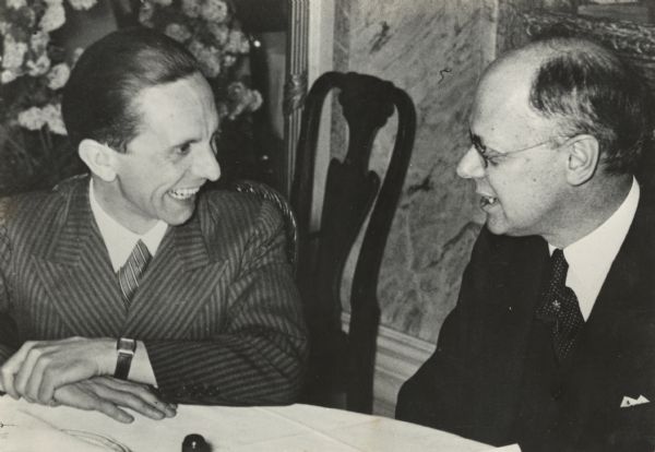German Propaganda Minister Joseph Goebbels and Louis P. Lochner, foreign correspondent, are having a conversation while seated at a table.