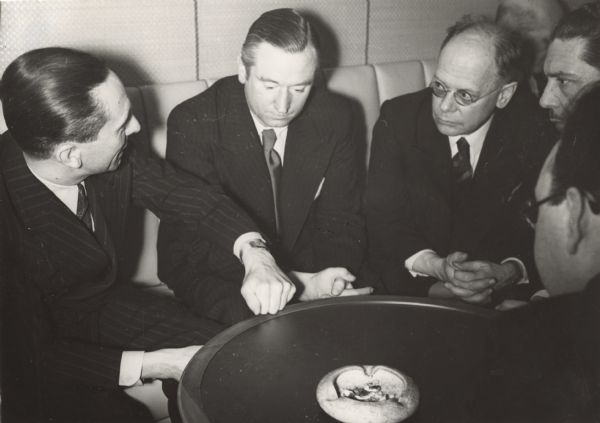 German Propaganda Minister Joseph Goebbels (left) and Louis P. Lochner, foreign correspondent (third from left) sit around a small round table with three other unidentified men.