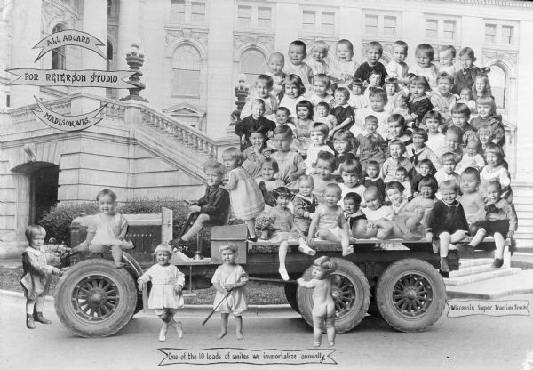 Composite photograph of 65 photographic prints of young children and infants, trimmed out and attached to the photograph of an open bed truck parked in front of the Wisconsin State Capitol. After the 65 prints and the text inside the banners were attached, the composite was rephotographed. The text reads, "All Aboard, For Reierson Studio, Madison, Wis." "One of the 10 loads of smiles we immortalize annually" and "Wisconsin Super Traction Truck."