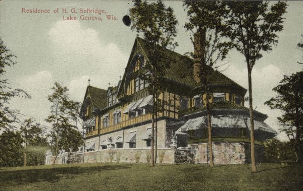Hand-colored postcard of the "Residence of H.G. Selfridge, Lake Geneva, Wis." The large Tudor influenced house has three stories and features a tall chimney and striped awnings. A stone wall partially obscures the first floor. H.G. Selfridge, a native of Ripon, Wisconsin, was a retail magnate who earned a fortune in Chicago and in 1908 moved to London where he established the department store which bears his name. He built this house on Geneva Lake in 1899, and named it Harrose Hall, combining a portion of his first name with that of his wife, the former Rose Buckingham. Selfridge owned the house until 1922; it was demolished in 1975.