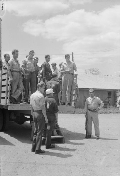 A work shift of German prisoners at a prisoner of war camp are being loaded onto a truck to be conveyed to work at a local cannery.