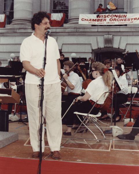 Mayor Soglin standing at the microphone as Honorary Host of Wisconsin Chamber Orchestra's Concerts on the Square.