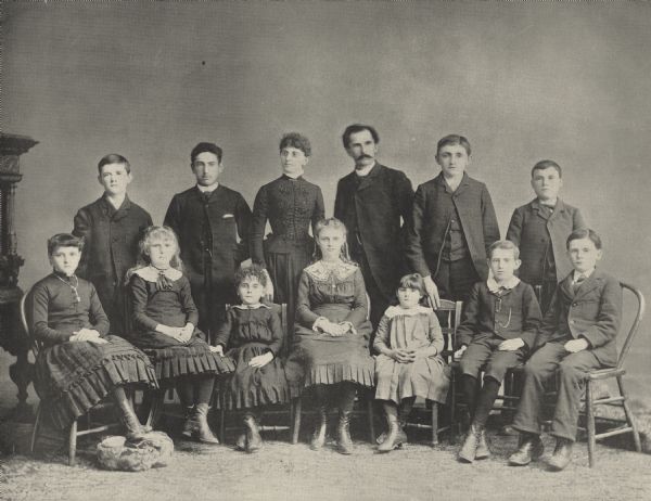 Formal group portrait of the students attending the Milwaukee Day School for the Oral Instruction of the Deaf. The first public day school for the deaf, established under the law of Wisconsin of 1885, providing for such schools in incorporated cities and villages with State aid, and constituting what is known as the "Wisconsin system of educating the deaf." Standing in the second row are Willie Malloy, Oscar Teweles, Frances Wettstein, Paul Binner, Willie Tischafer and Patrick Ryan. Sitting in the first row are Lizzie Rundle, Hypatia Boyd, Katie Elias, Lillie Koerner, Ida Hirsch, Willie Howard and Frank Harnitz.