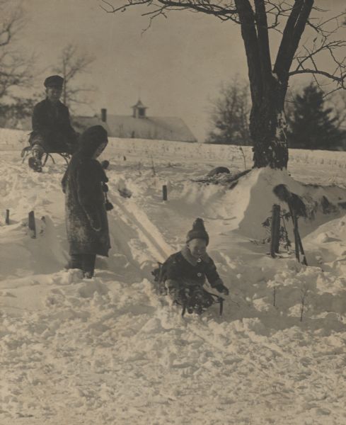 Laurie, Muriel, and James Peterson, children of the photographer, sledding near the family home. Handwritten on reverse, "Laurie, Muriel, James Peterson, children of Carl Peterson."