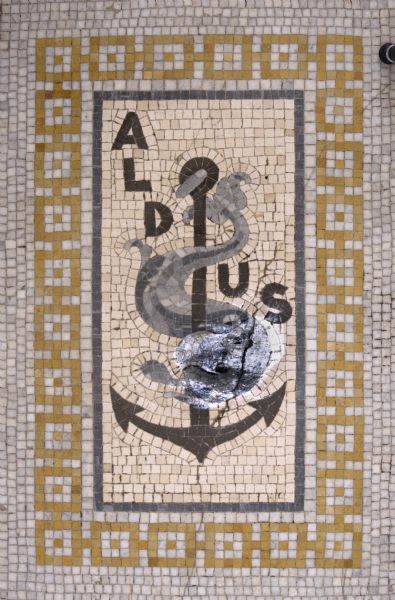 Mosaic in the south lobby floor of the Wisconsin Historical Society. This design, dating from 1502, was the mark of Aldus Manutius, the head of the printers of Venice. The anchor and the fish reflect the city-state's maritime economic base.<p>The Aldine family press used a variety of marks throughout its existence (1492-1598), and all incorporate the anchor and dolphin image.</p> 