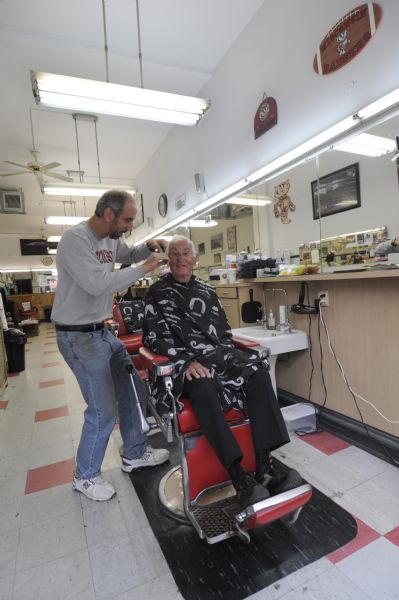 The last week of business at the College Barber Shop. The owner Larry Cobb is cutting employee Don Fine's hair.