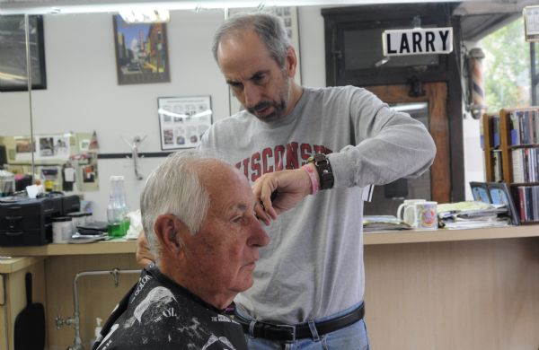 The last week of business at the College Barber Shop. The owner Larry Cobb is cutting employee Don Fine's hair.