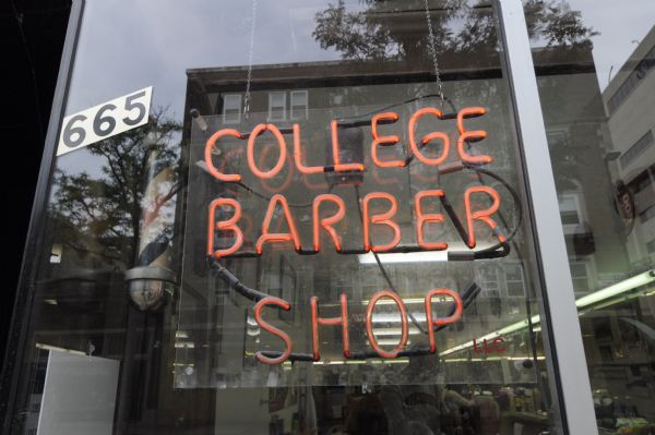 Exterior view of the College Barber Shop at 665 State Street during their last week in business. In the window is a neon sign and a traditional barber's pole.