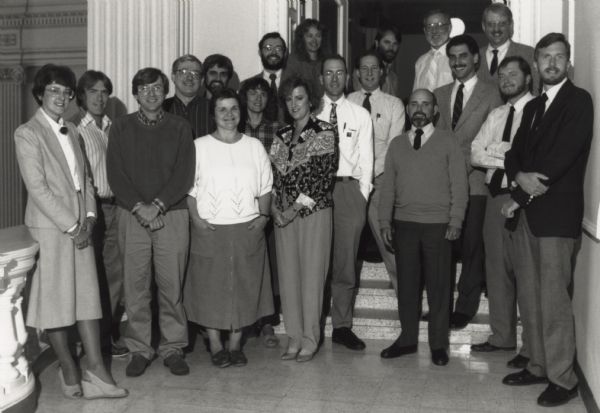 Group portrait of the Division of Historic Preservation at the Wisconsin Historical Society. Names, back row, l to r: Dan Duchrow, Rick Dexter, Brian McCormick, Paul Lusignan, Jim Draeger, Rick Bernstein, Rod Riggs, Larry Reed, Joe DeRose, Jeff Dean. Front row, l to r: Kathy Long, Paul Kreisa, Judy Patton, Diane Holliday, Donna Amacher, Jennifer Kolb, Bob Birmingham, Dave Cooper, Jim Sewell. Not pictured: Debra Cravens and Gretchen Block.