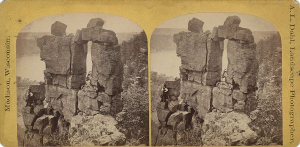 A man poses on a rock formation named "Devil's Doorway" at Devil's Lake State Park. The lake is visible in the background.