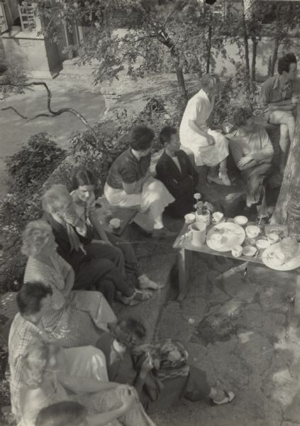 Overhead view of Frank Lloyd Wright and others gathered together outdoors for afternoon tea.