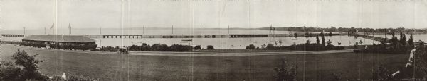 Panoramic view of Brittingham Bay taken from the north west shore of Brittingham Park. The boathouse is on the left. On the right the railroad tracks cross. In the foreground is North Shore Drive. In the background is Lake Monona. Printed fold-out in rare book, <i>Madison Park and Pleasure Drive Association 1907-1916.</i> Report of the officers of the Madison Park and Pleasure Drive Association.