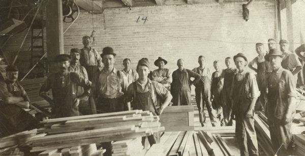 Indoor group portrait of male employees at the Starck Manufacturing Company. Caption reads: "In 1893, Mr. John H. Findorff became a member of the Starck Mfg. Co. Gradually, following the death of his partners, he bought the business on Washington Ave."