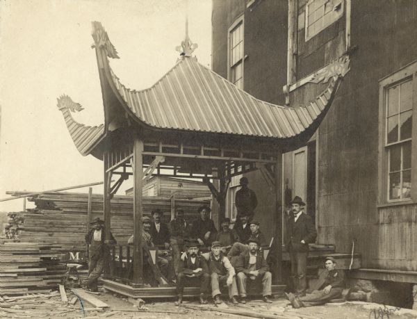 Findorff staff posing outdoors with a building under construction. The pavilion has a pagoda-style roof. There is a large building next to the group on the right, and stacks of lumber are behind them.