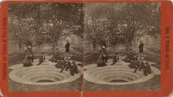 Stereograph of a group of men and women relaxing around a spring with concentric steps of limestone. The man on the right, holding the dipper, is Dr. Hugo Philler, a Waukesha physician. Behind the trees, in the background, is a horse-drawn buggy. Originally known as "Orchard Spring," the name was changed to "Asahel Spring" by Asahel Hawley Heath who bought it in 1875. He advertised the spring water as a cure for disease. This stereograph was the basis for his trademark. Eventually the spring vanished due to the dredging of the Fox River and a formal garden built in the 1920s. Caption on side reads: "Views of Waukesha and Vicinity."