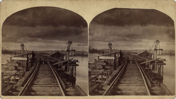 Stereograph of John Lawler's pile-pontoon railway bridge over both channels of the Mississippi River at Prairie du Chien and McGregor, Iowa. The East Draw is 396 feet long, looking west. A sign on the bridge reads: "No Person Allowed To Walk Over This Bridge." Listed on reverse: "No. 11. East Draw 396ft long, looking west."