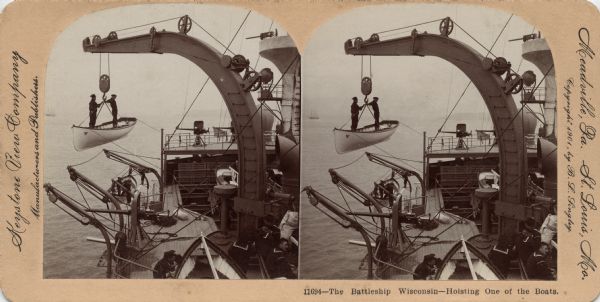 Stereograph of two sailors standing in a small boat as it is hoisted aboard the Battleship "Wisconsin." More sailors are in the lower right corner. Caption reads: "11694 — The Battleship Wisconsin — Hoisting One of the Boats."